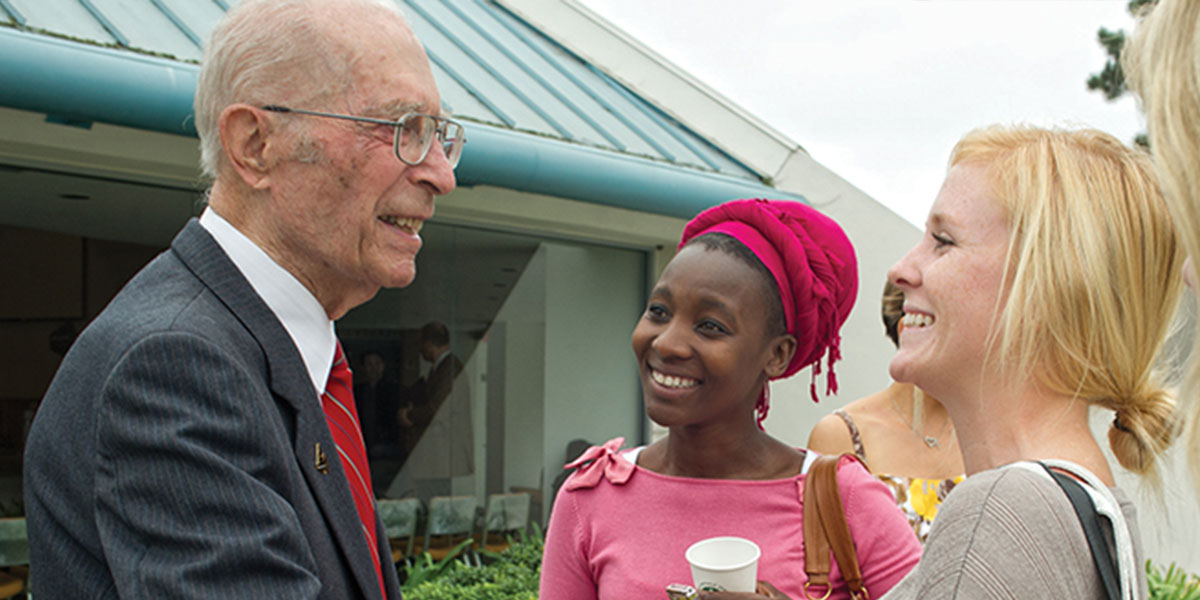 Alfred Neukuckatz talking to two female students outside the CU Center